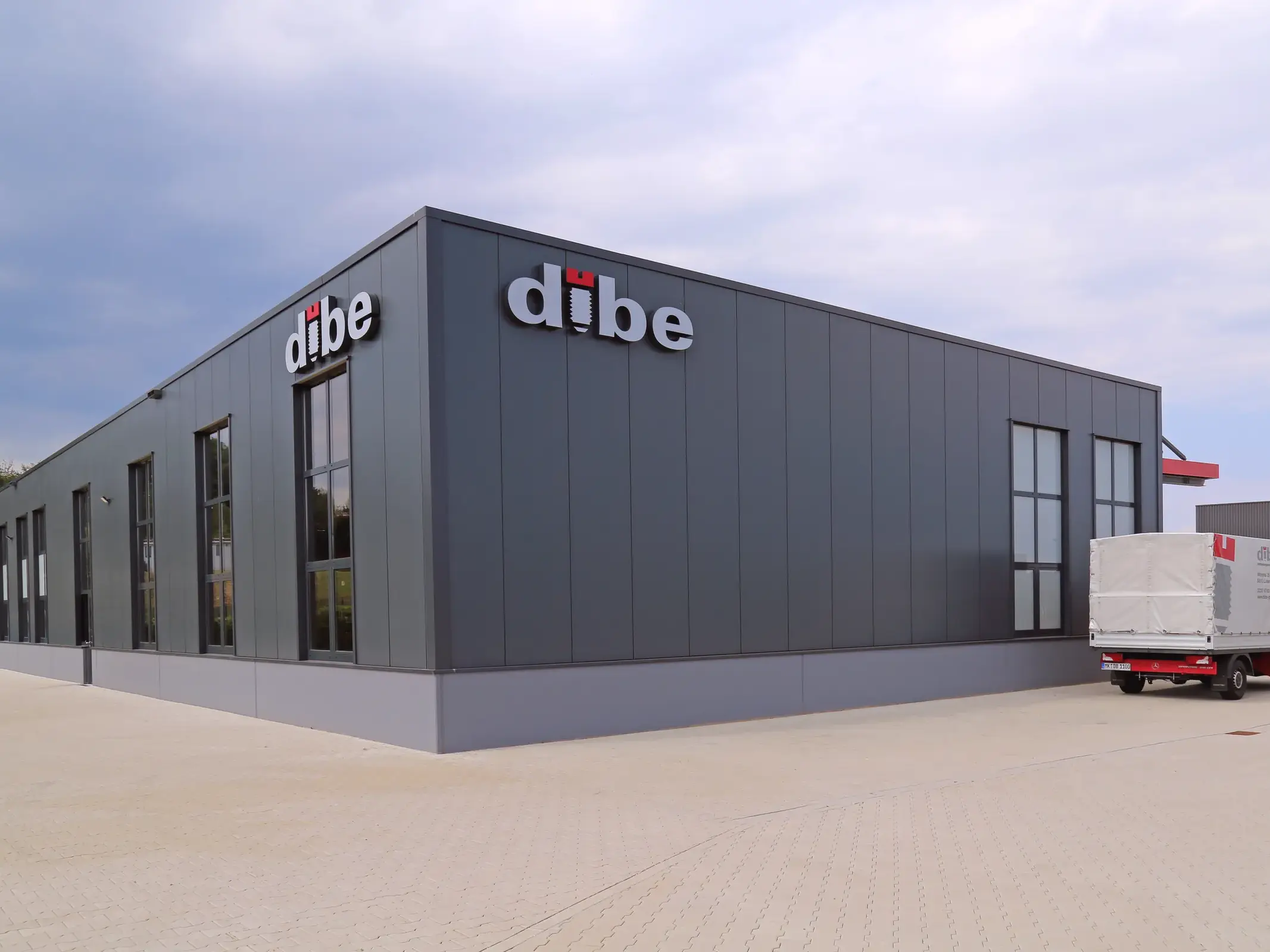 Betriebsneubau Dibe in Lüdenscheid: anthrazitfarbene Halle mit Schriftzug und Fensterbändern