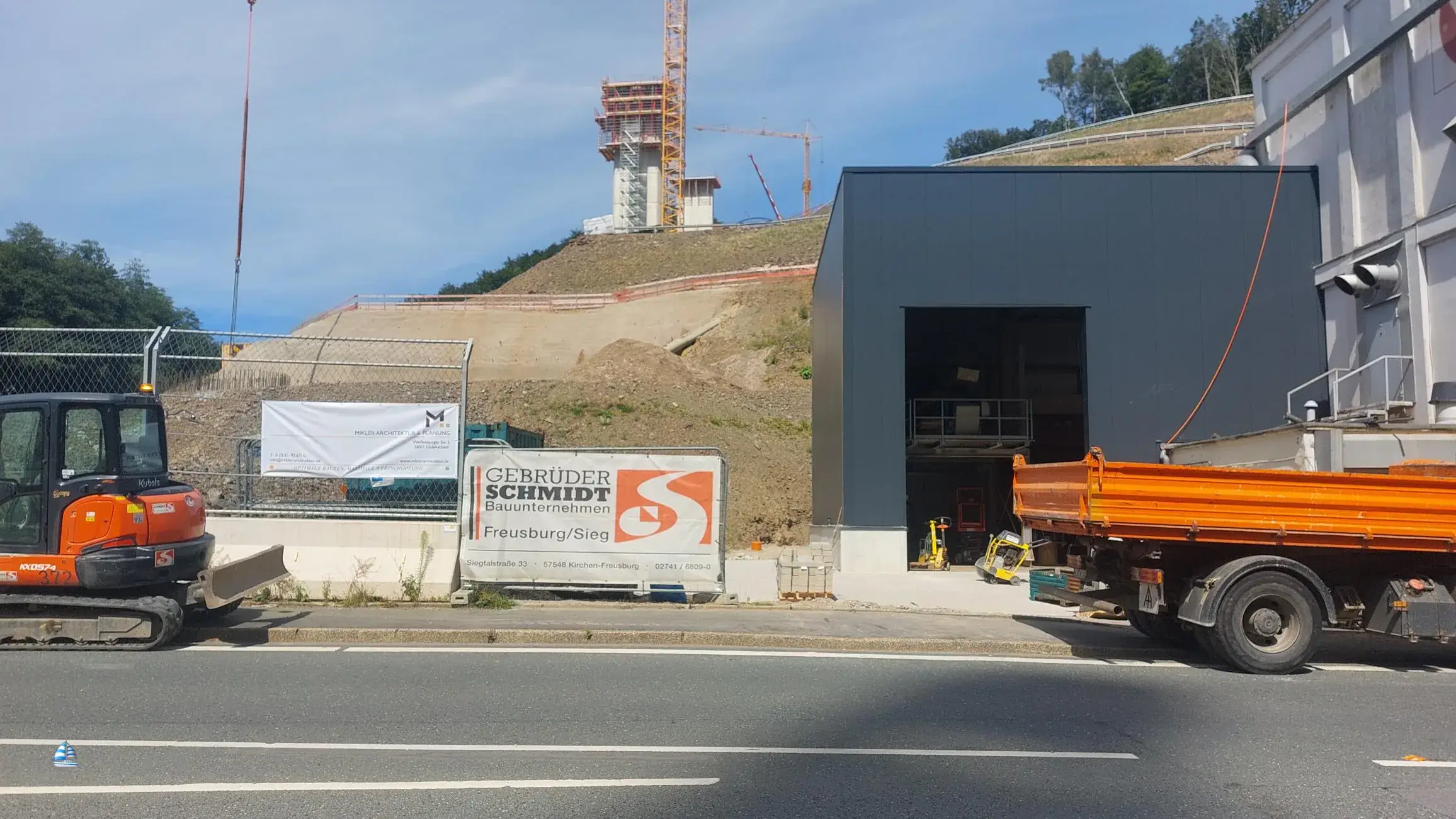 Betriebserweiterung Immel Seckelmann in Lüdenscheid: dunkler Neubau an der Straße, dahinter der Hang