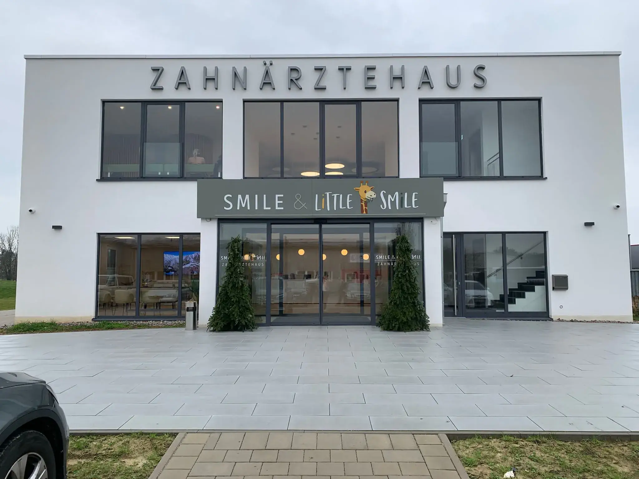 Zahnärztehaus in Renchen: weißer Baukörper mit großer Glasfront und Schriftzug über dem Eingang