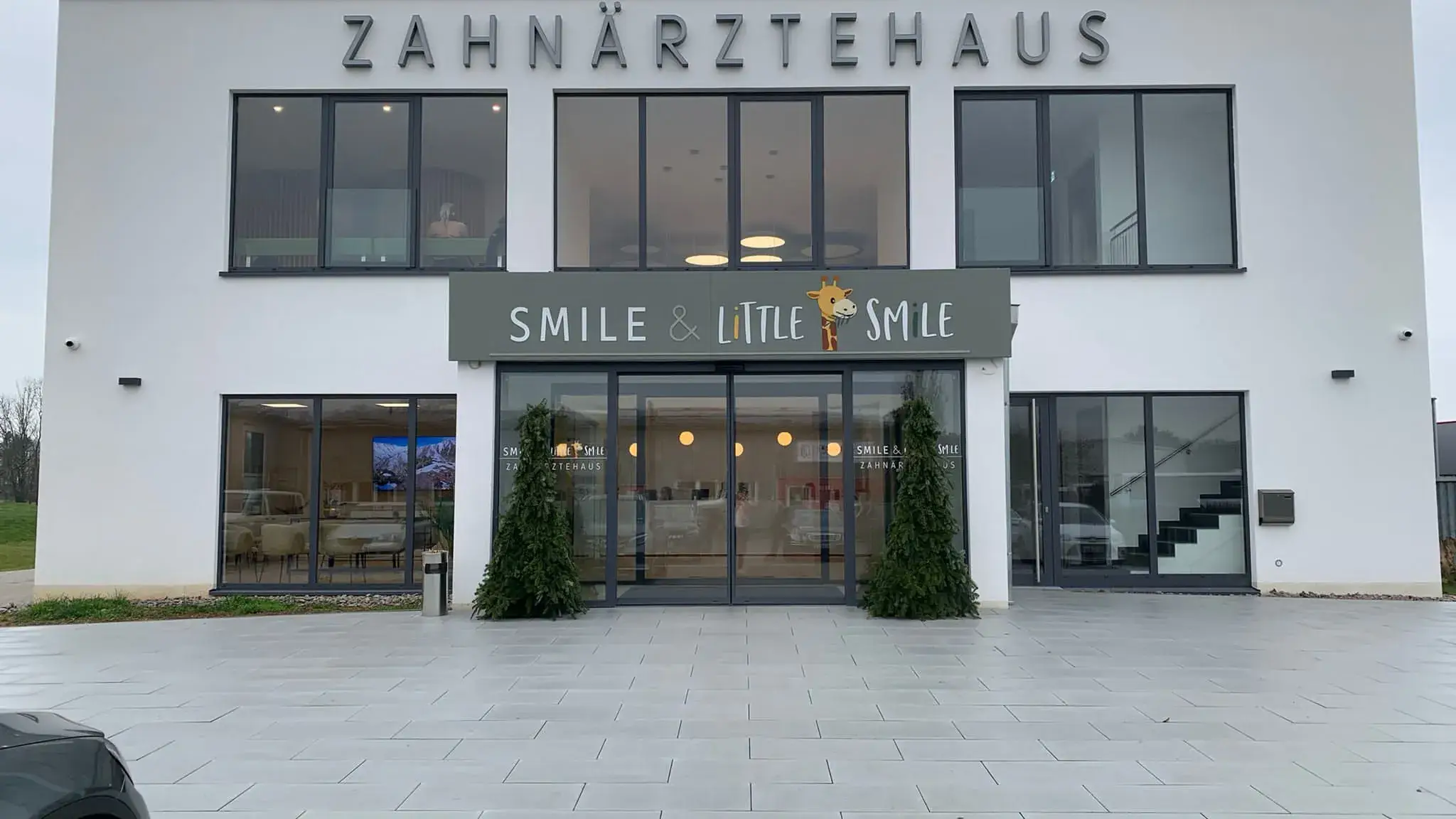 Zahnärztehaus in Renchen: weißer Baukörper mit großer Glasfront und Schriftzug über dem Eingang